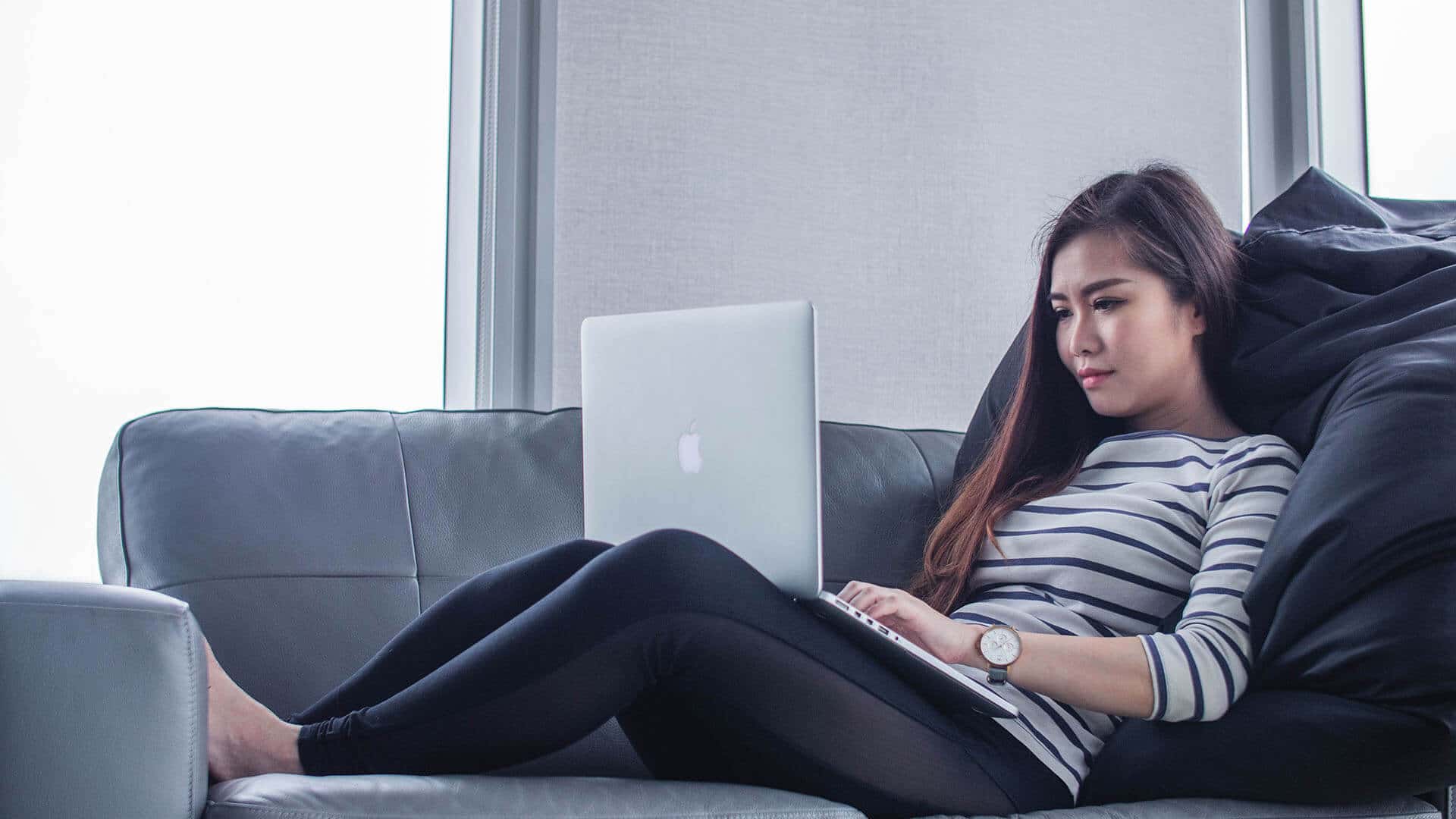 Photo of woman looking at computer on couch